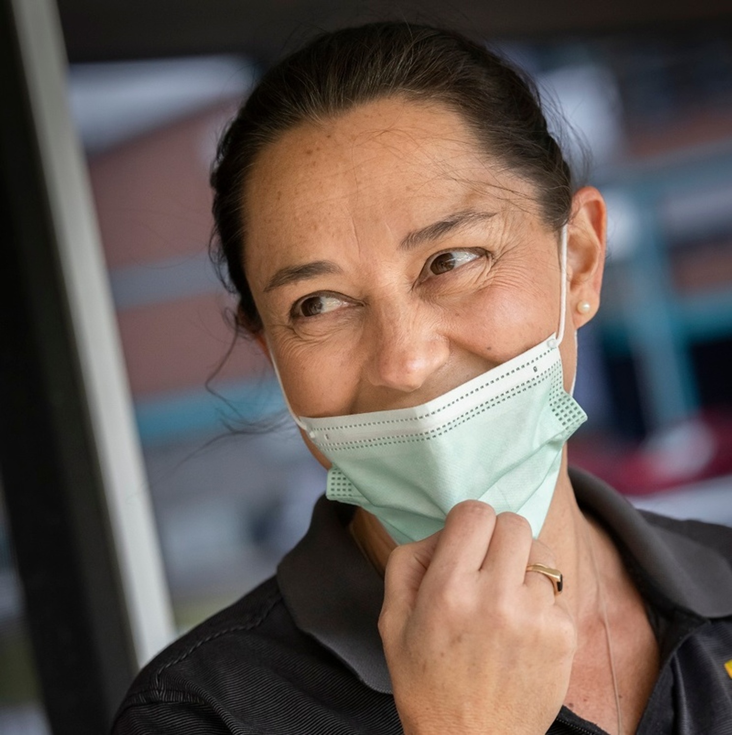 A woman pulls her mask down to reveal a smile