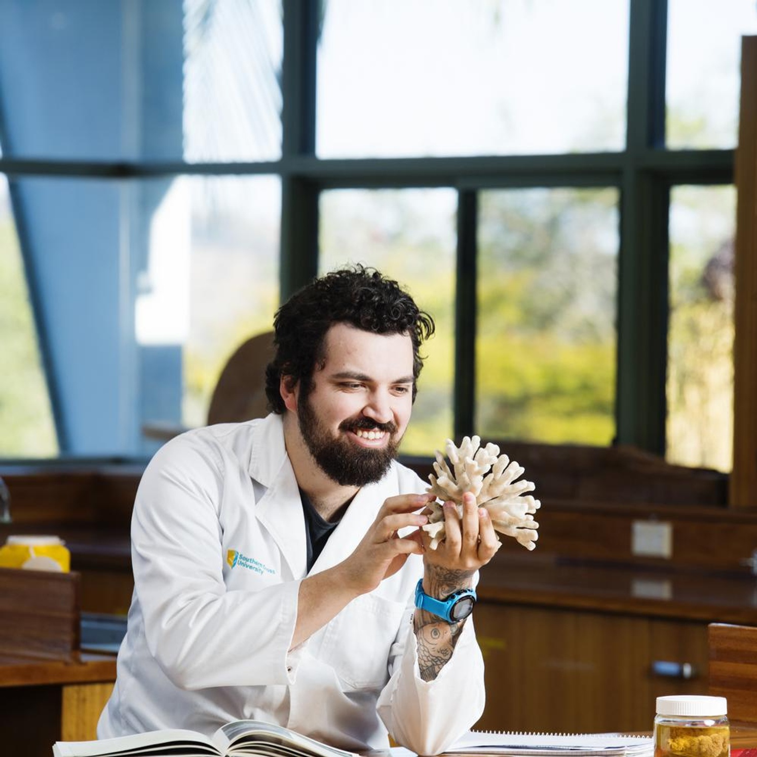 Jordan Ivy looking at a piece of coral in a lab