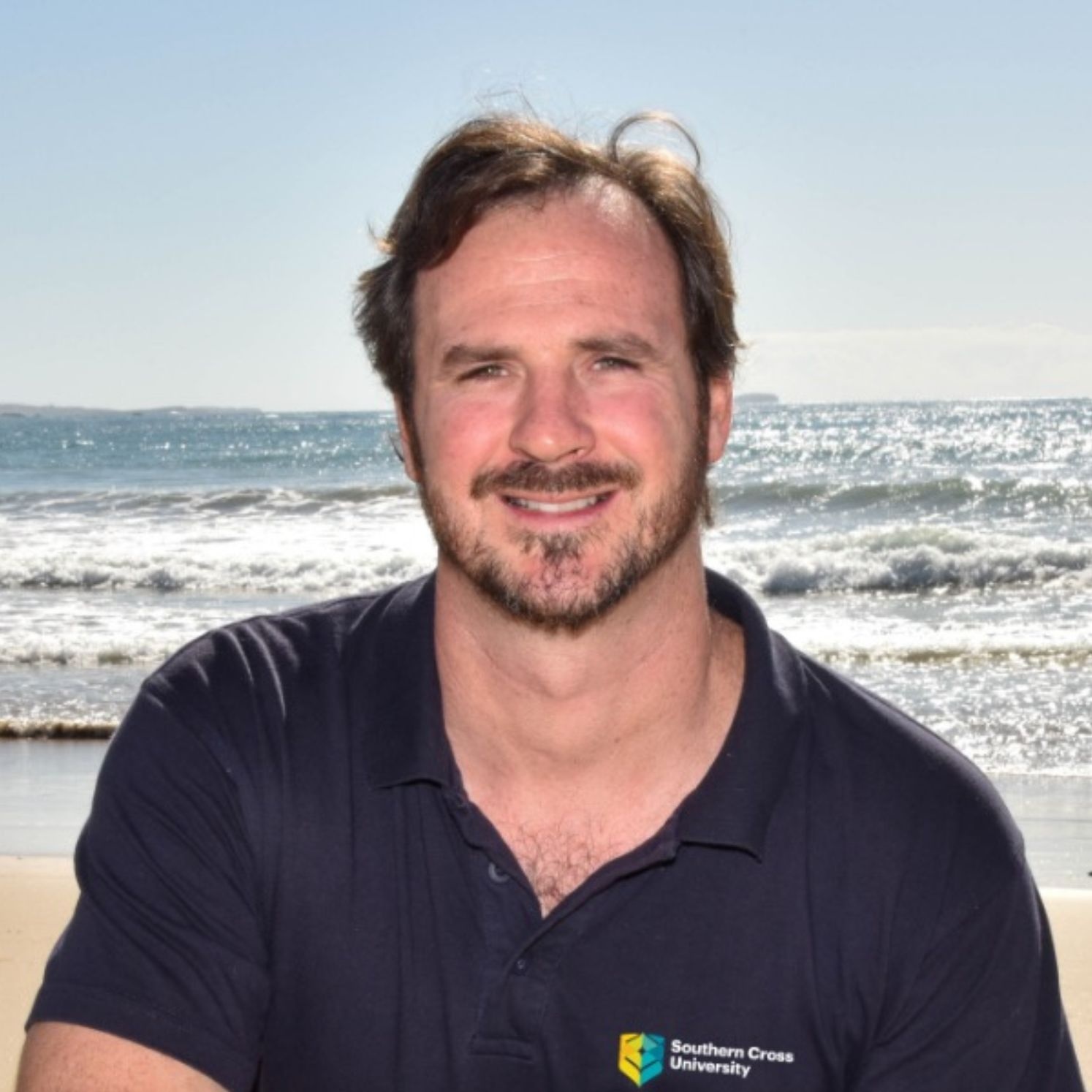 Dr Daniel Harrison standing in front of ocean