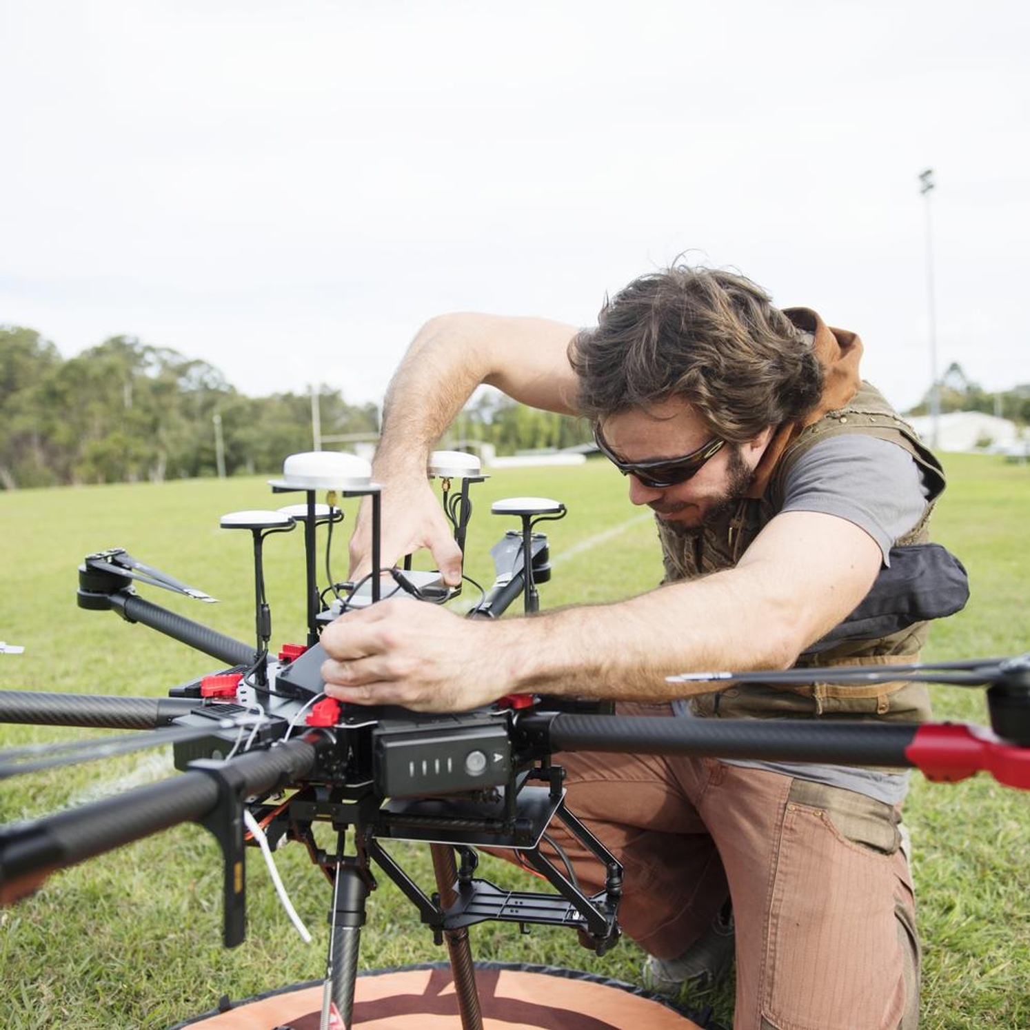 A researcher working on a drone on a green lawn