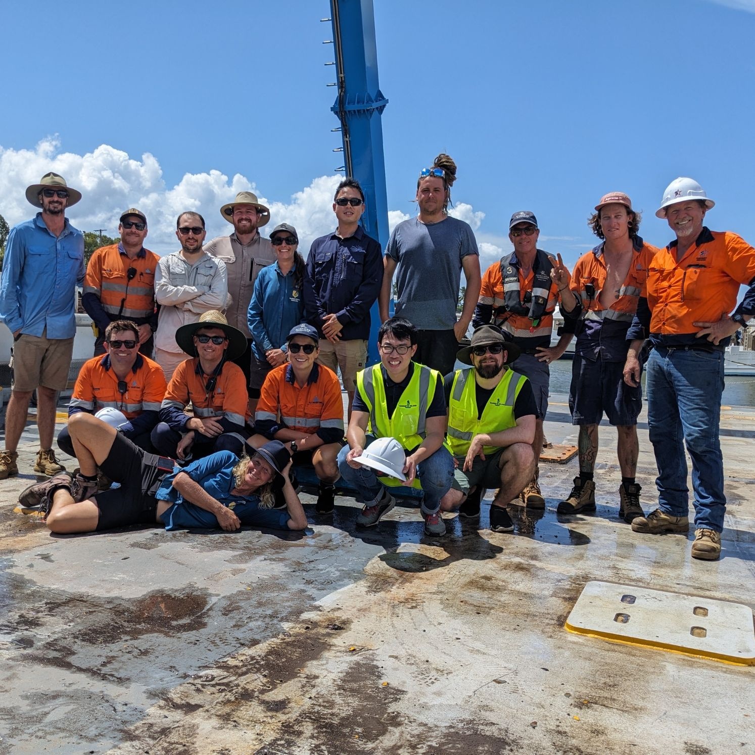 Large group of people in high vis workwear smiling on board a large boat