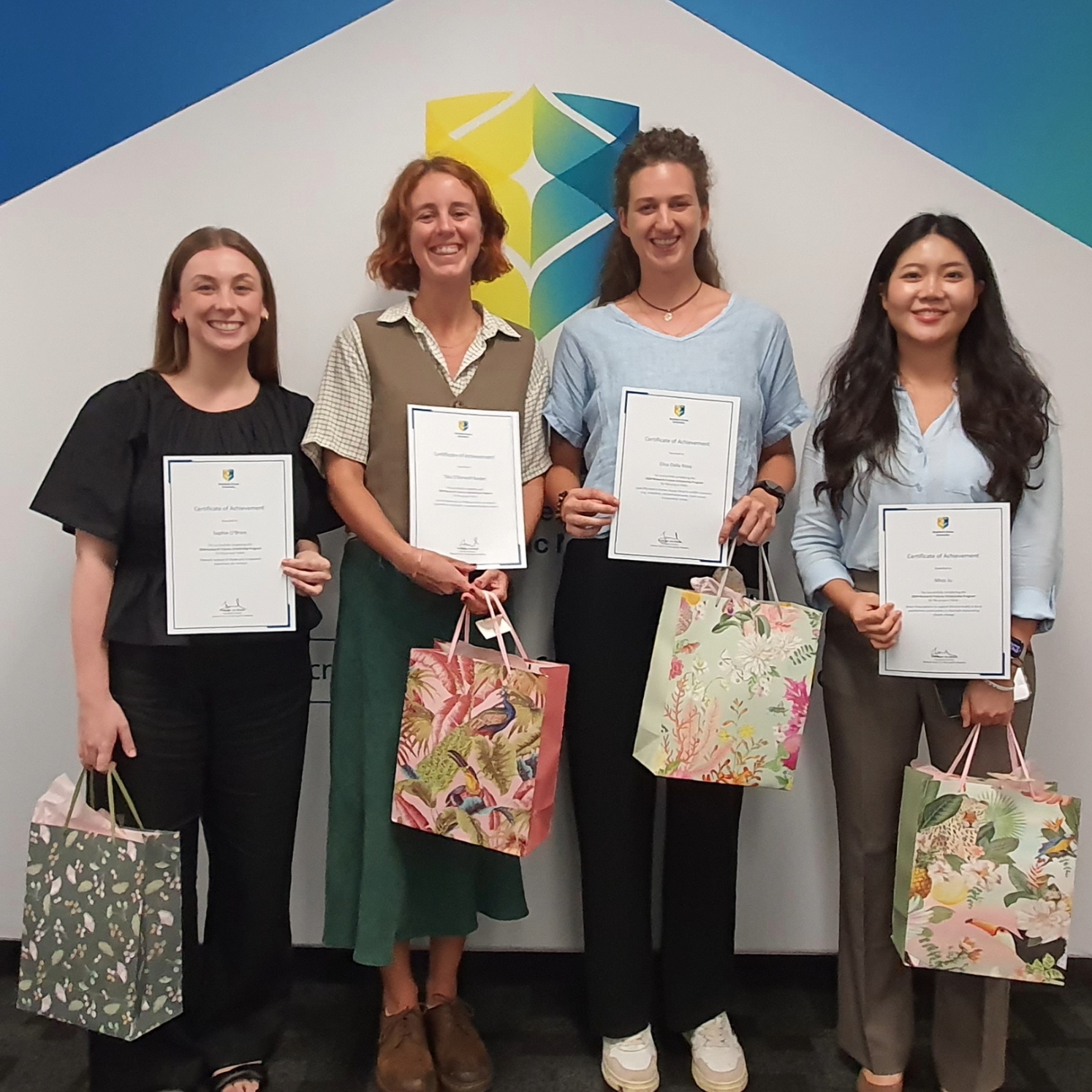 Four RFSP students at a presentation with gifts and certificates