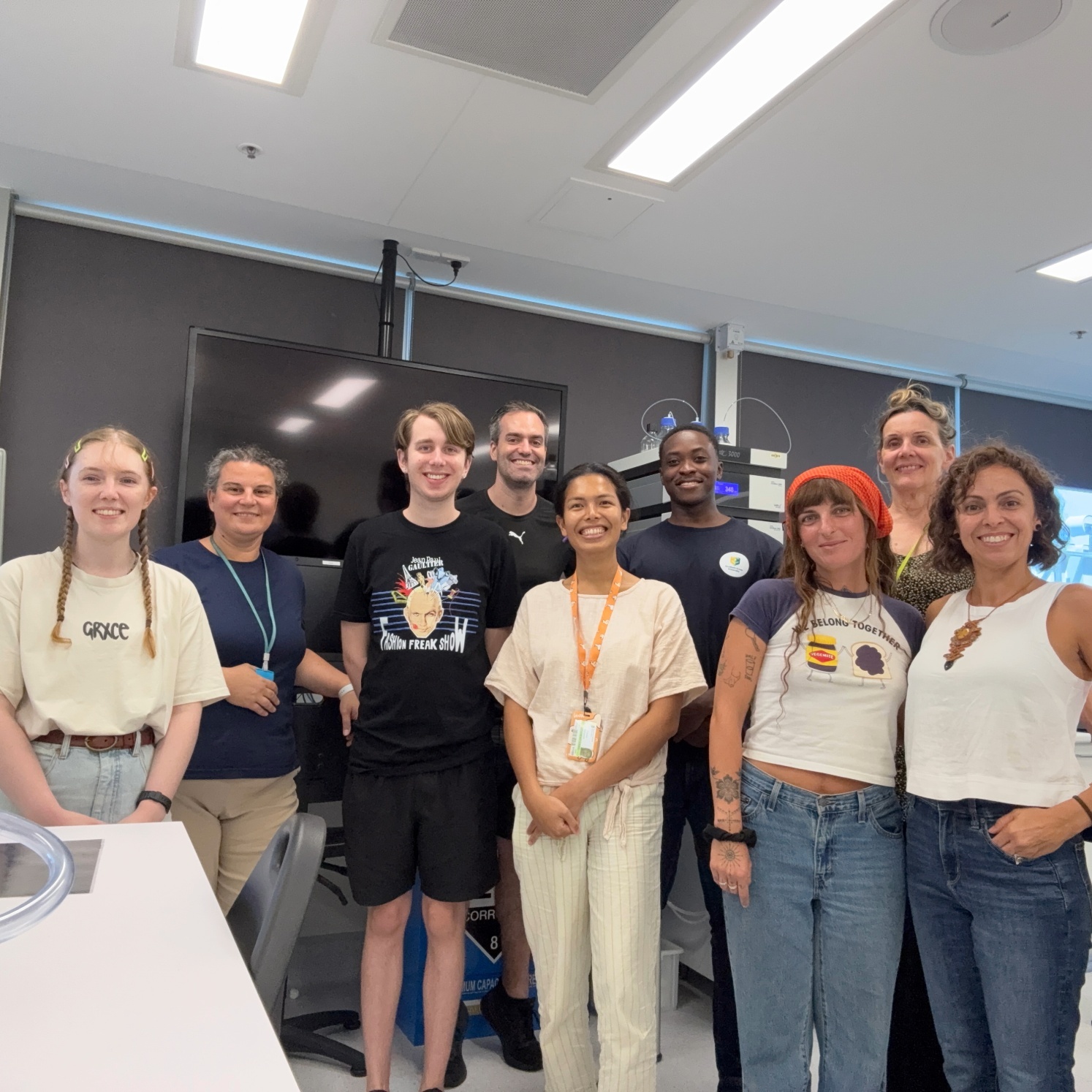 A group of students and supervisors in a lab smiling at the camera