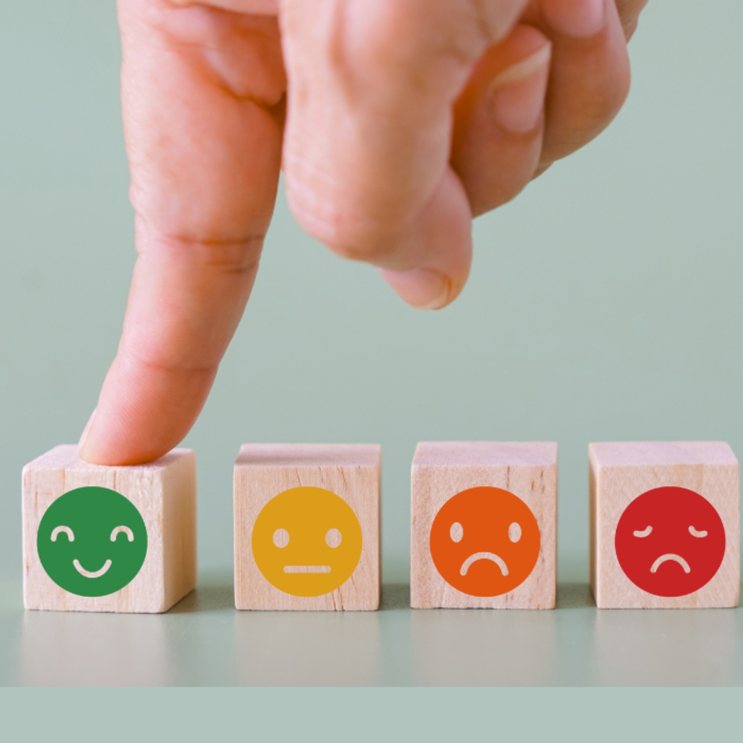 The Wellbeing Continuum shows finger resting on smily face block