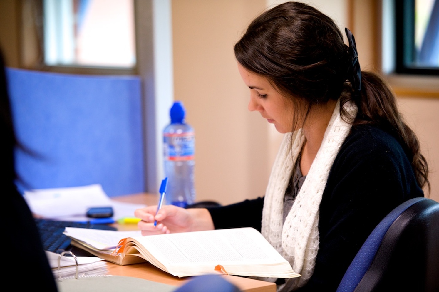 A student doing research at a desk with pen and paper