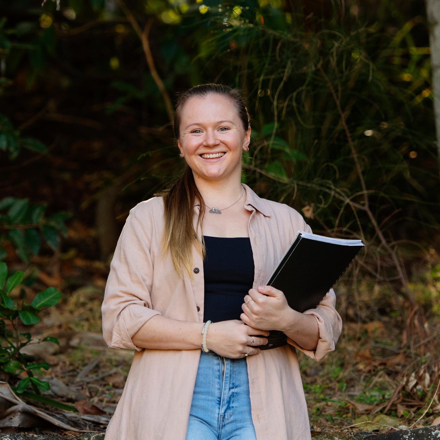 Student smiling with book in hand