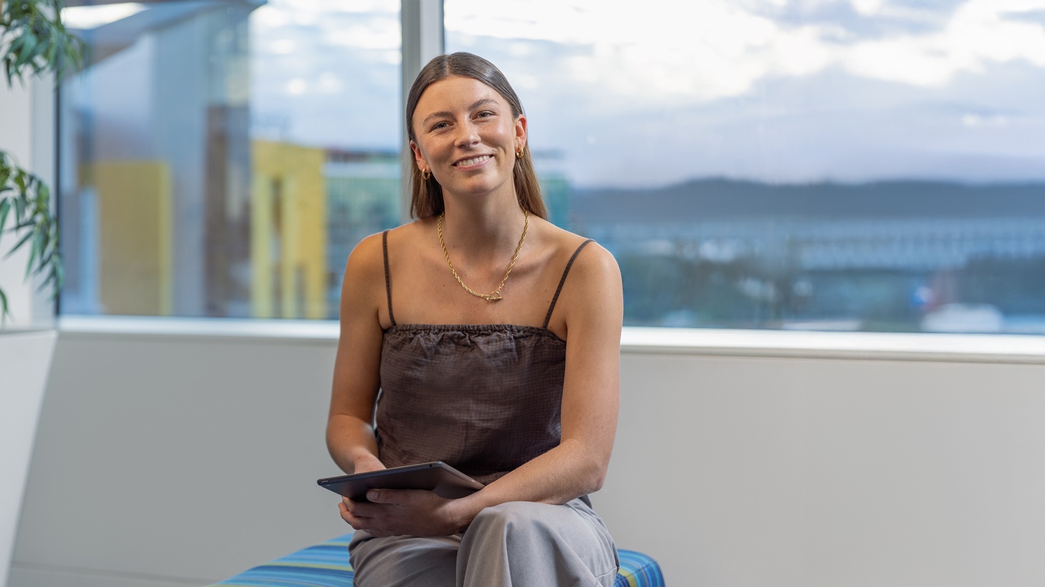 Psychology student sitting with tablet smiling