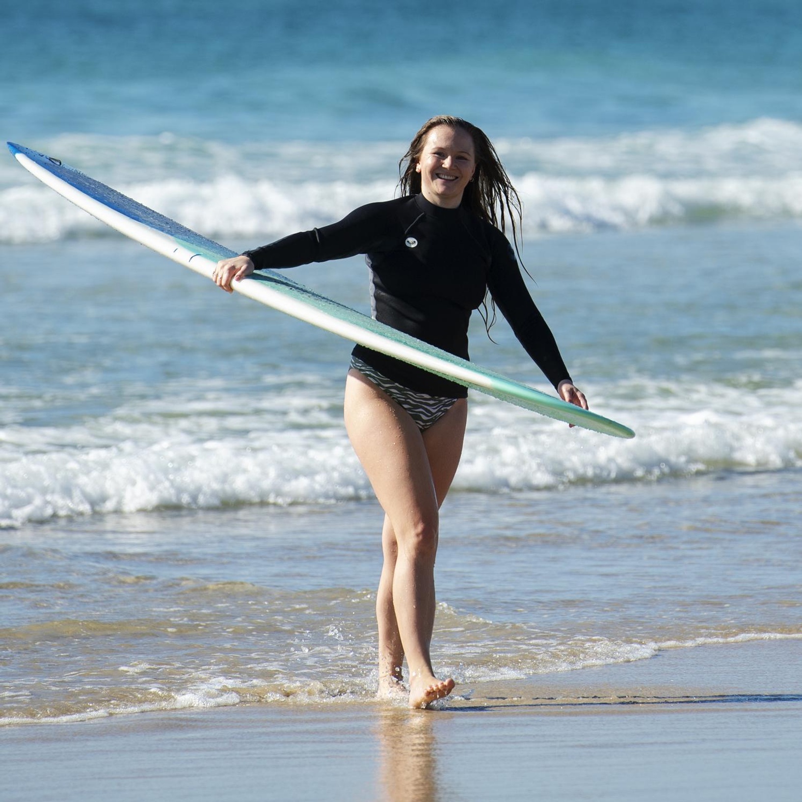 Student at the beach with a surfboard