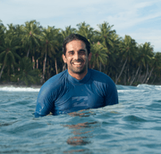 Smiling man in the ocean by palm tree beach