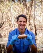A man in a wetland forest holding a piece of bark