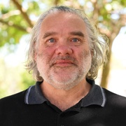 profile style photo of man wearing black polo shirt, looking at camera