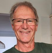 profile style photo of man smiling at camera, wearing green tshirt and glasses
