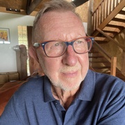 Man in blue shirt wearing red glasses looking off into distance