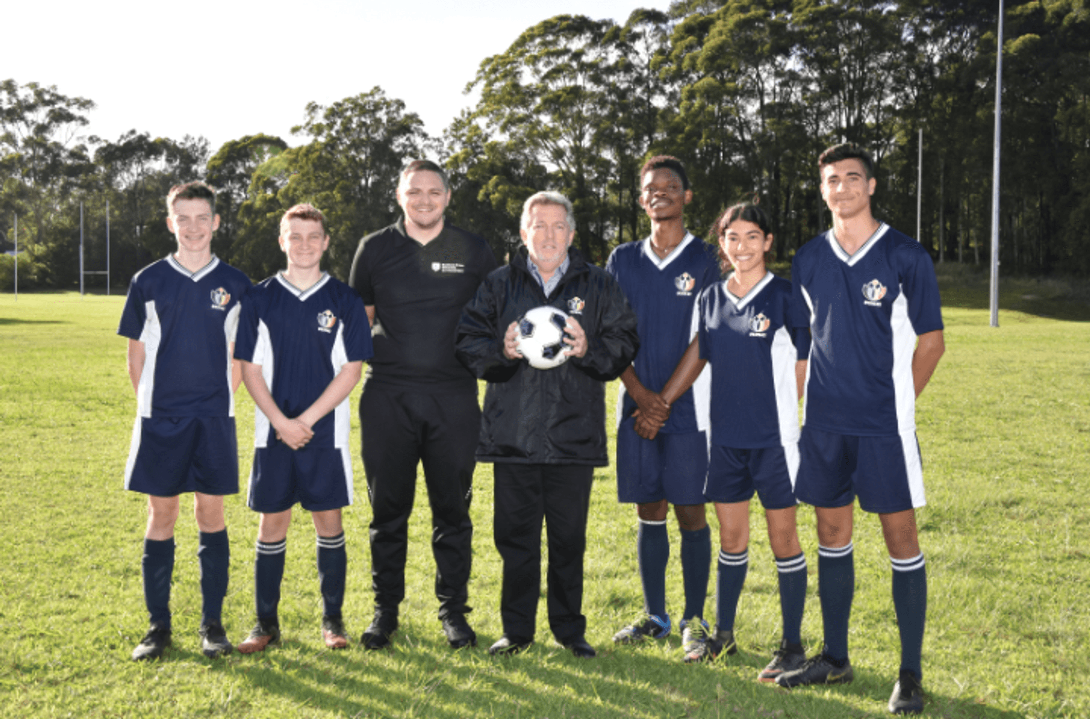 A group of young soccer players standing alongside two adults
