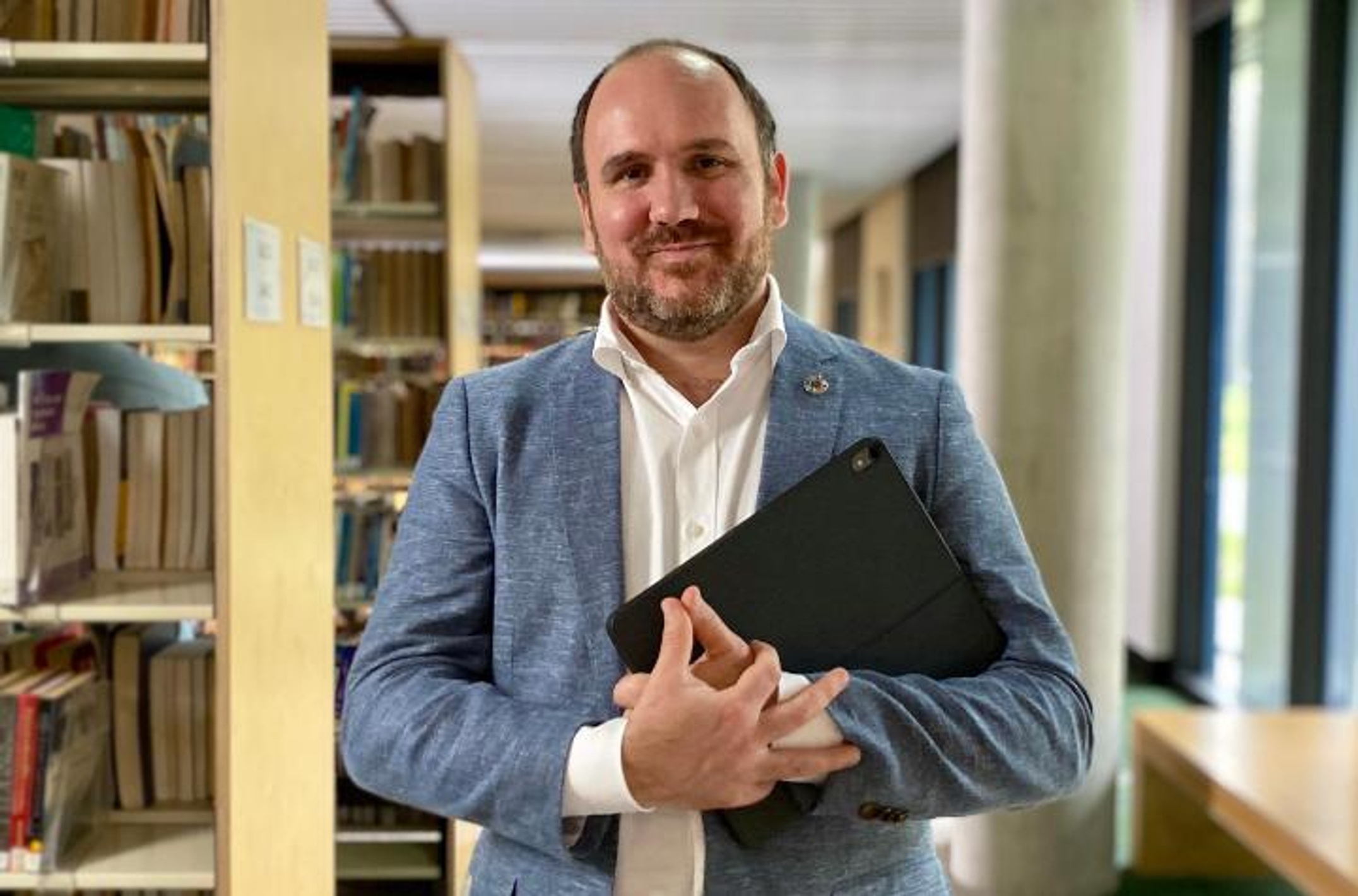 Man holding laptop in a library