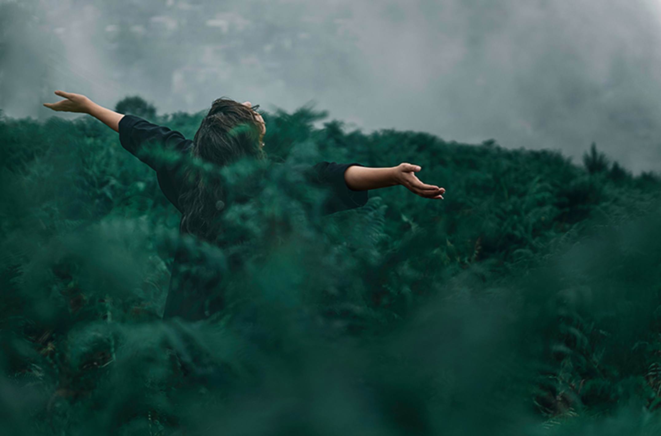 woman standing in field of green branches