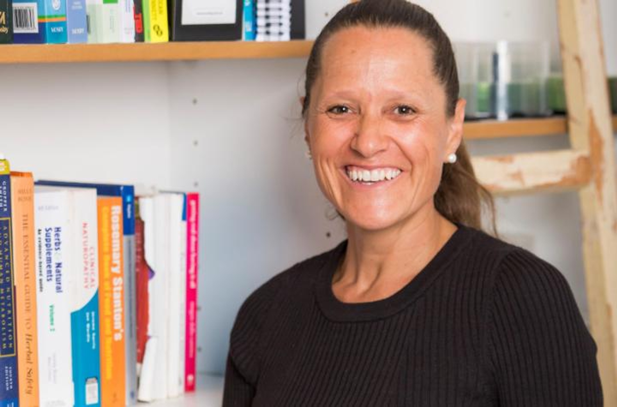Woman smiling in front of a bookcase