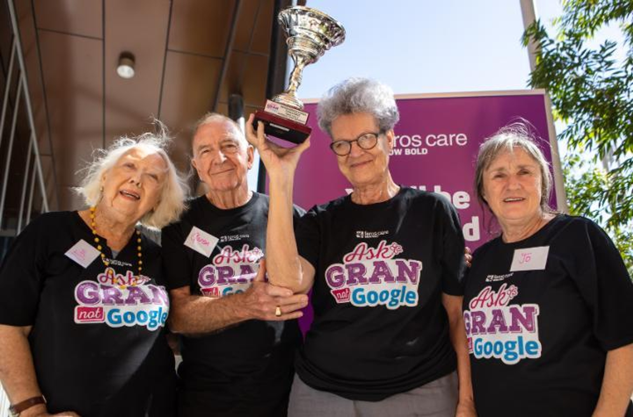 A group of senior citizens holding a winner's trophy.