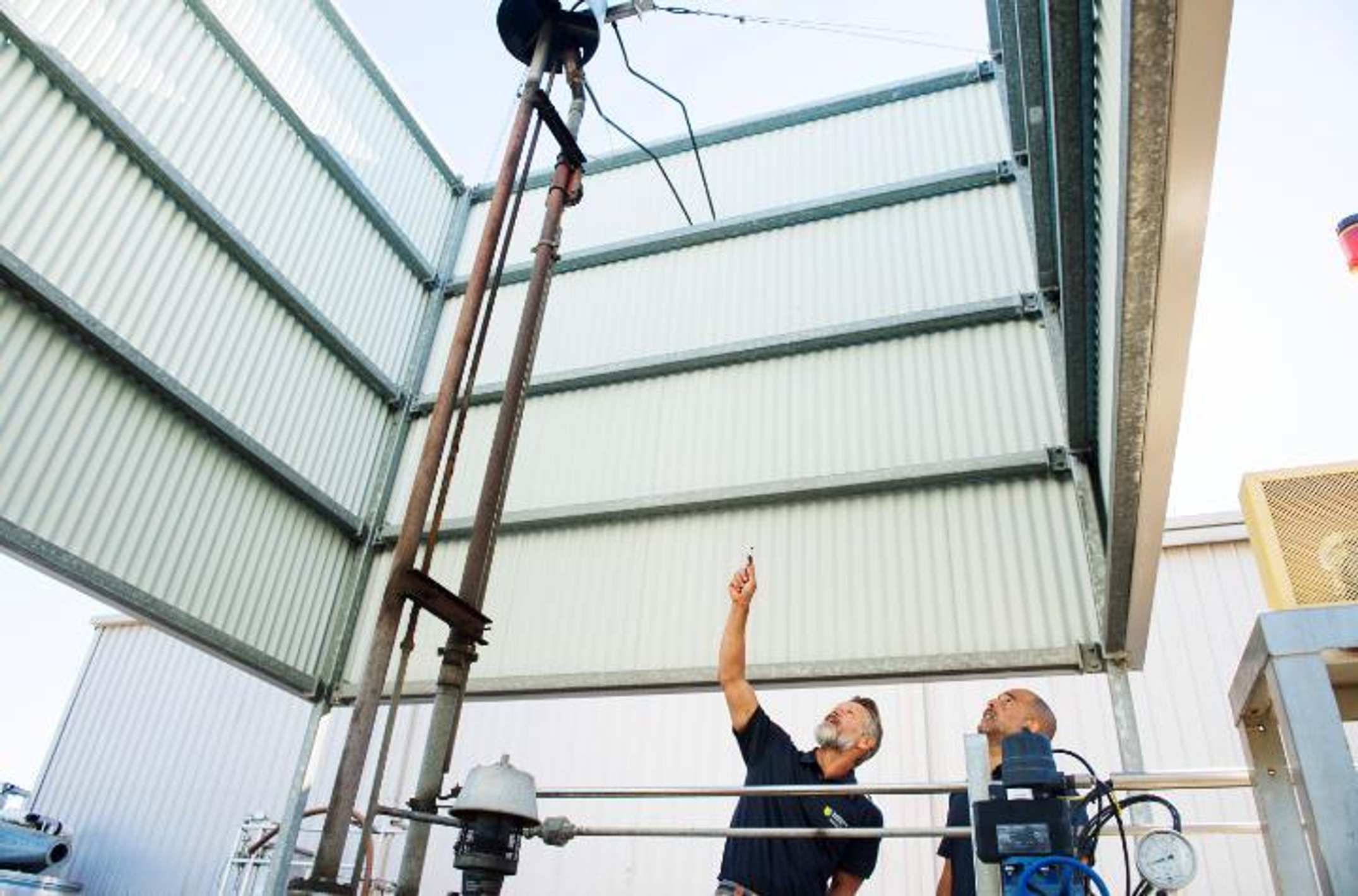 Two men inside a facility and looking up at equipment