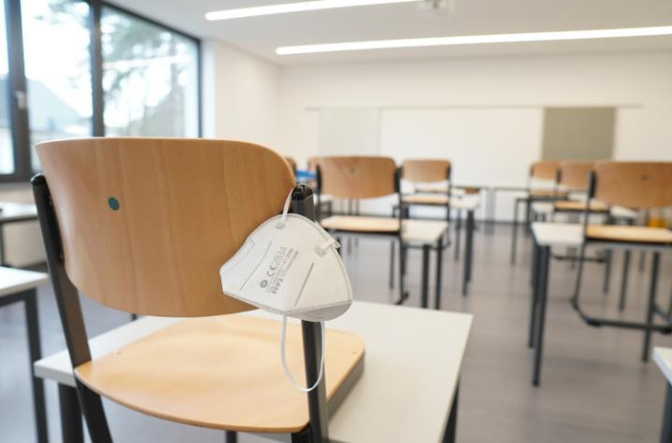 Empty classroom with facemask slung over a chair