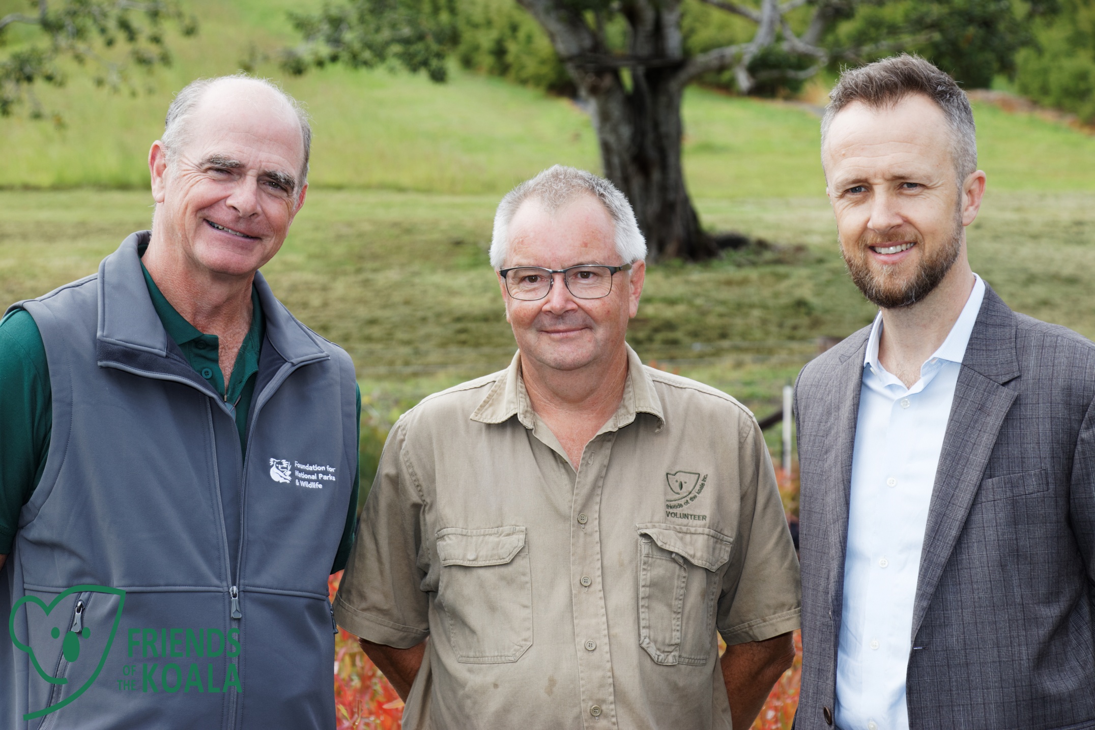 Three men in a paddock in front of a tree