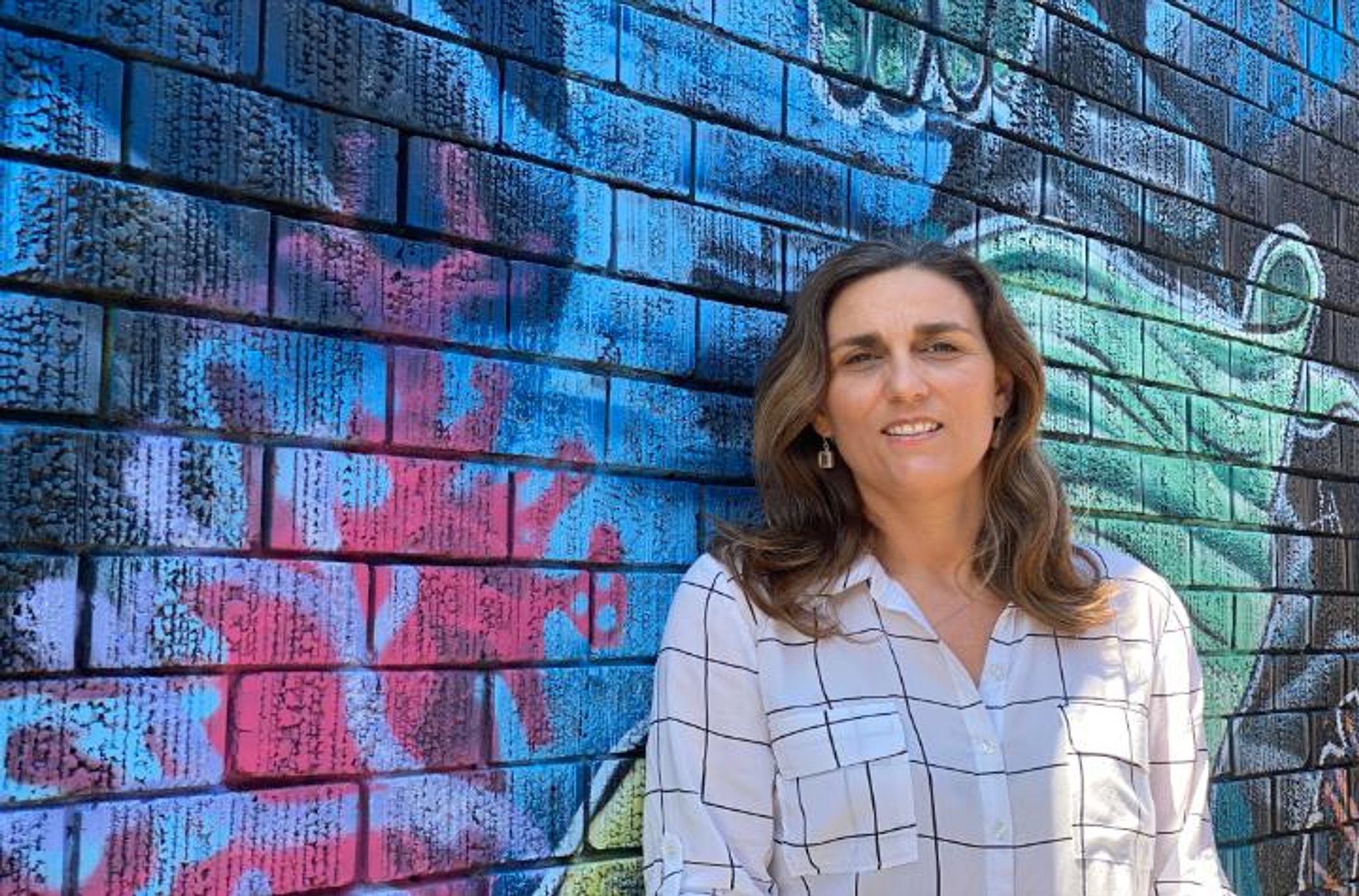 Woman leans against a colourful wall