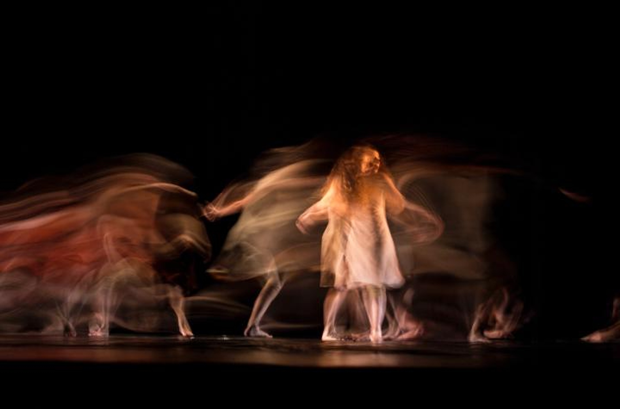 A woman with long hair and white dress moving across a stage