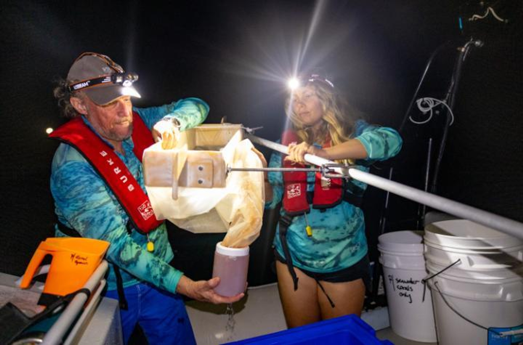A man and woman working at night on a boat collecting spawn
