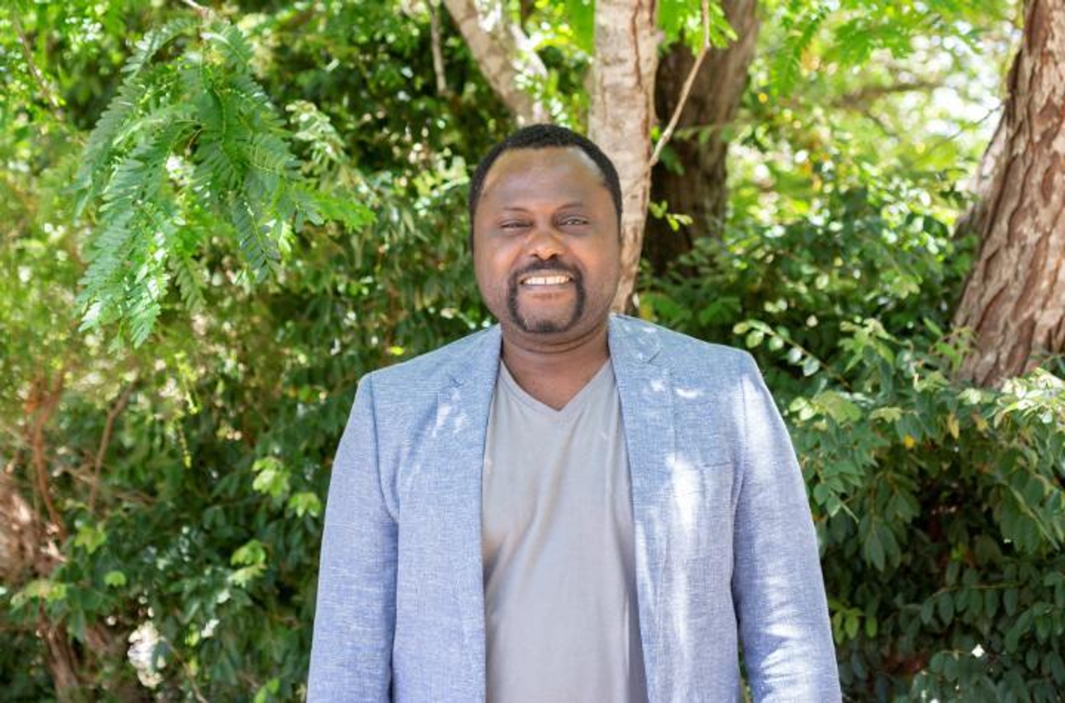 Man in business jacket in front of trees