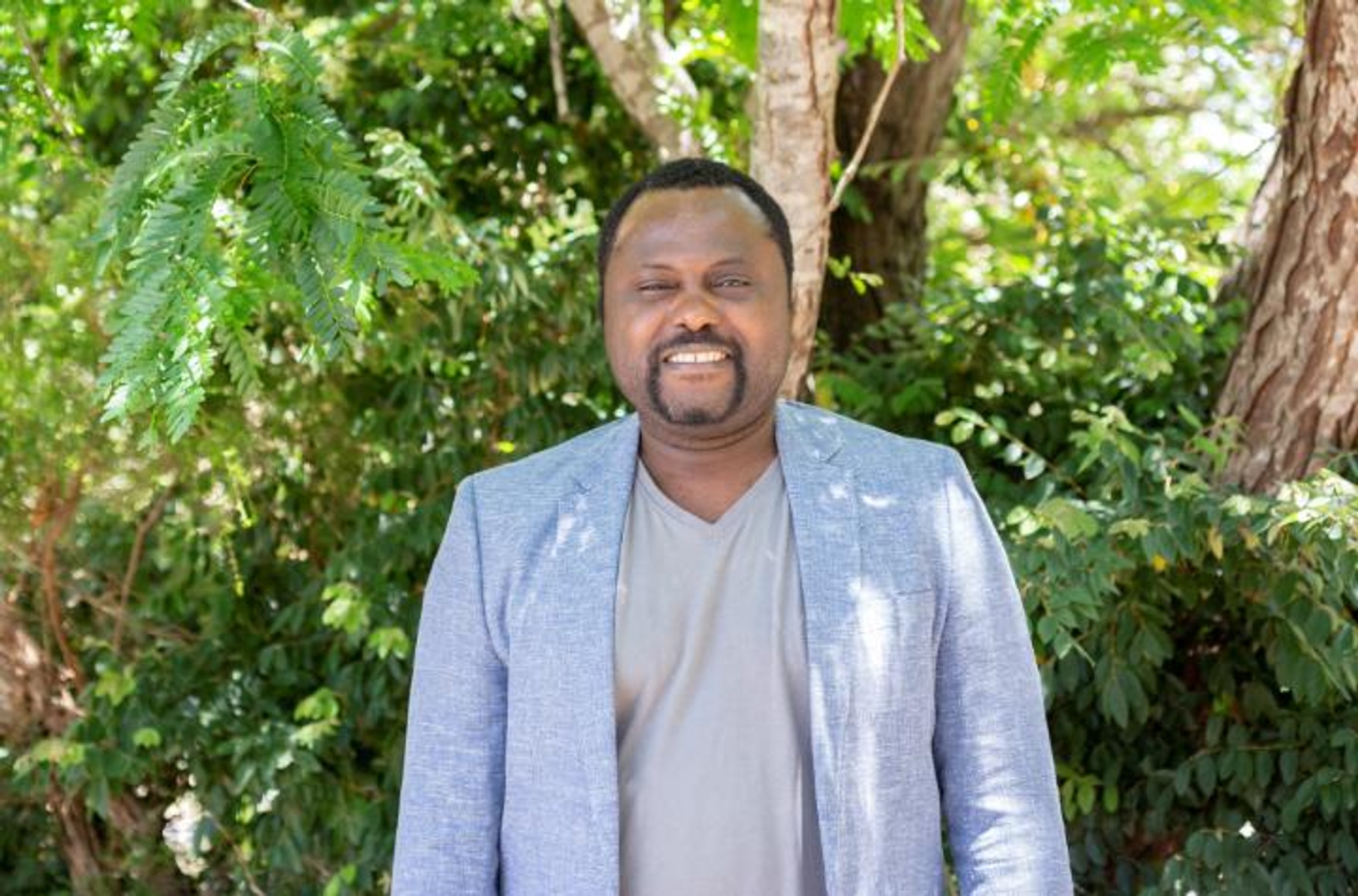 Man in business jacket in front of trees