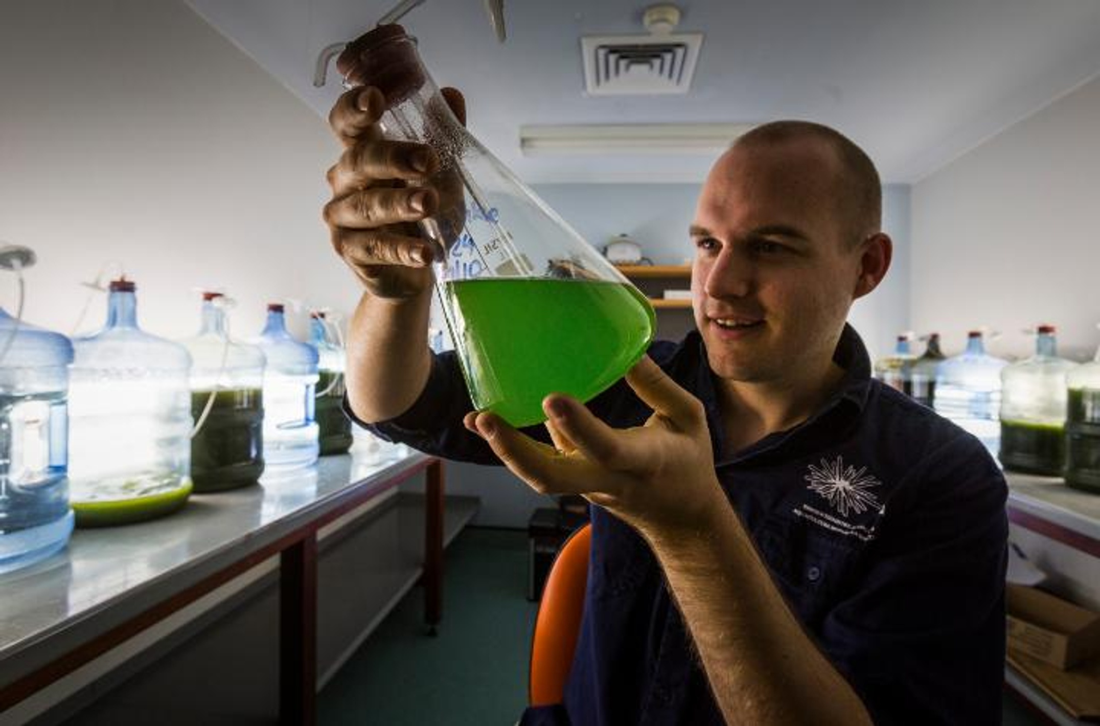 Scientist holds up beaker with green liquid