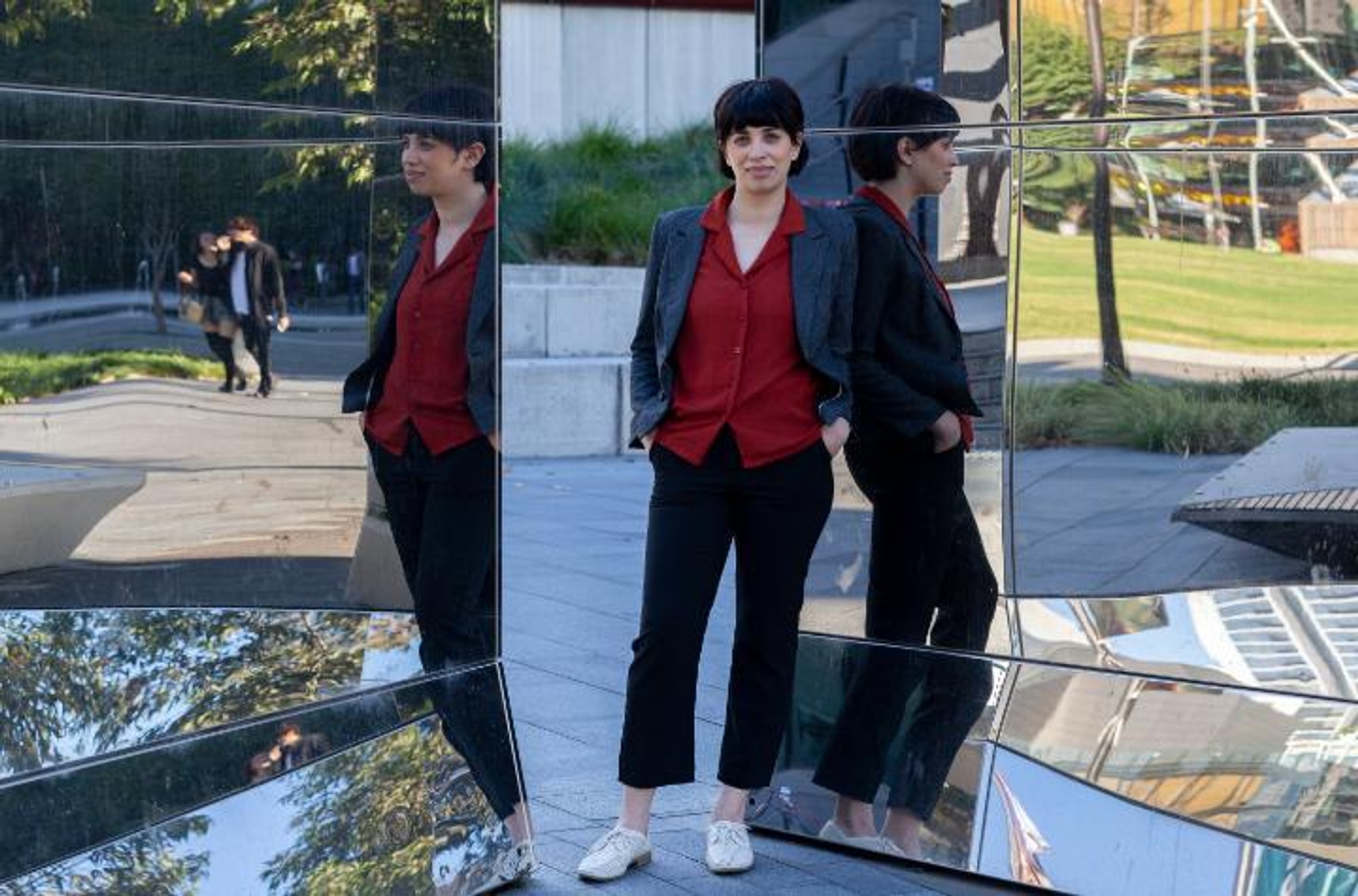 A woman stands in front of curved mirrors