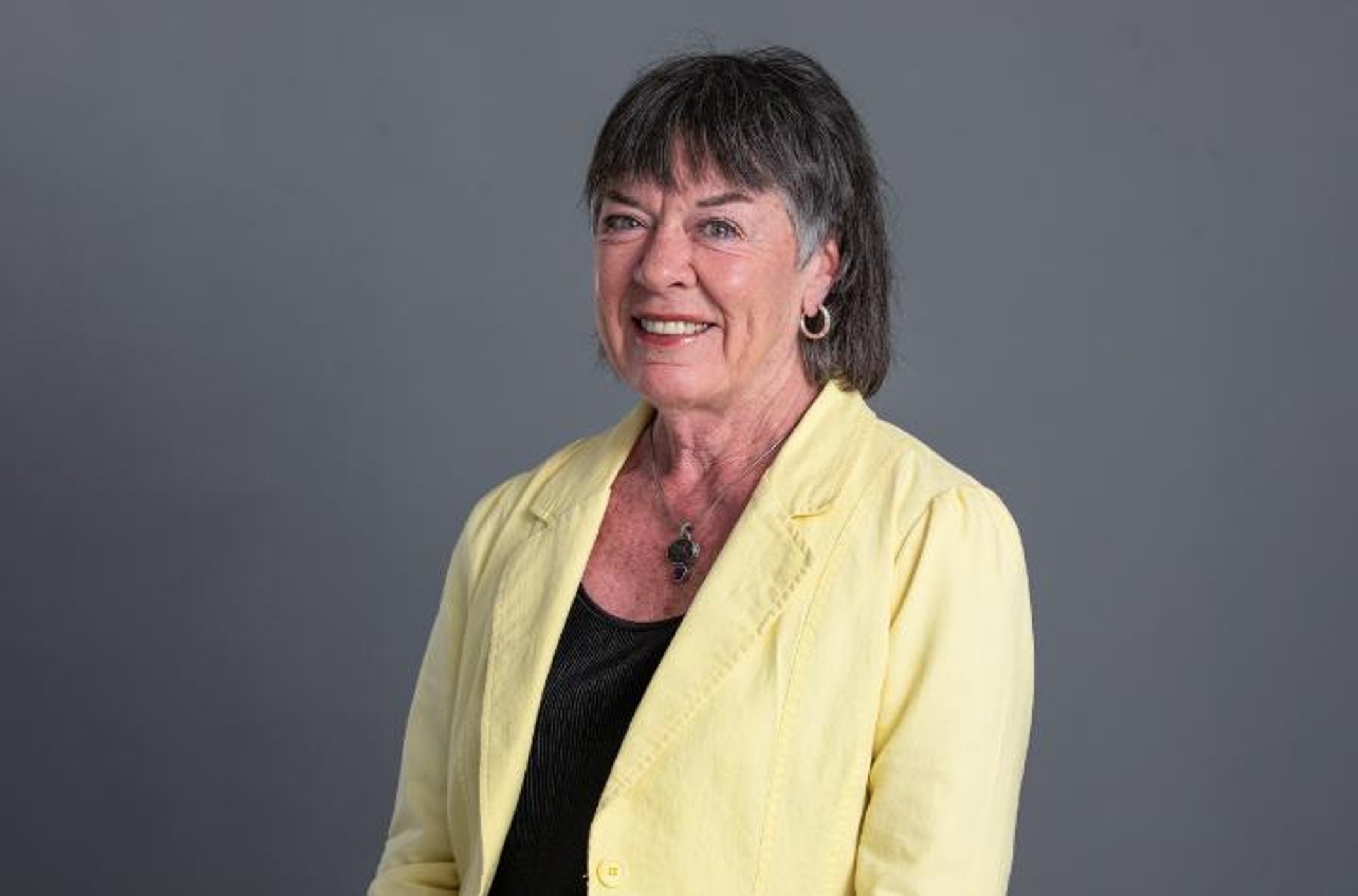 A woman wearing a yellow jacket and black top