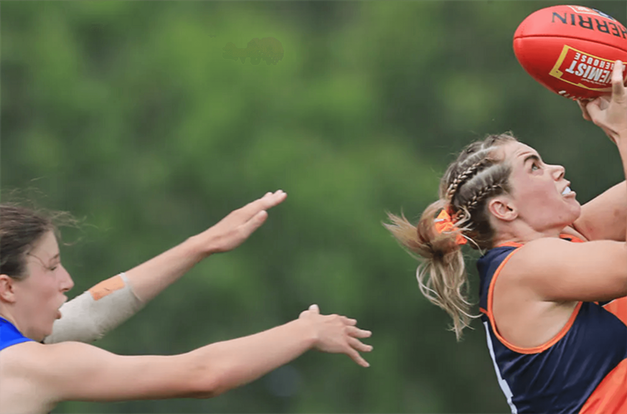 Two women playing AFL taking a mark