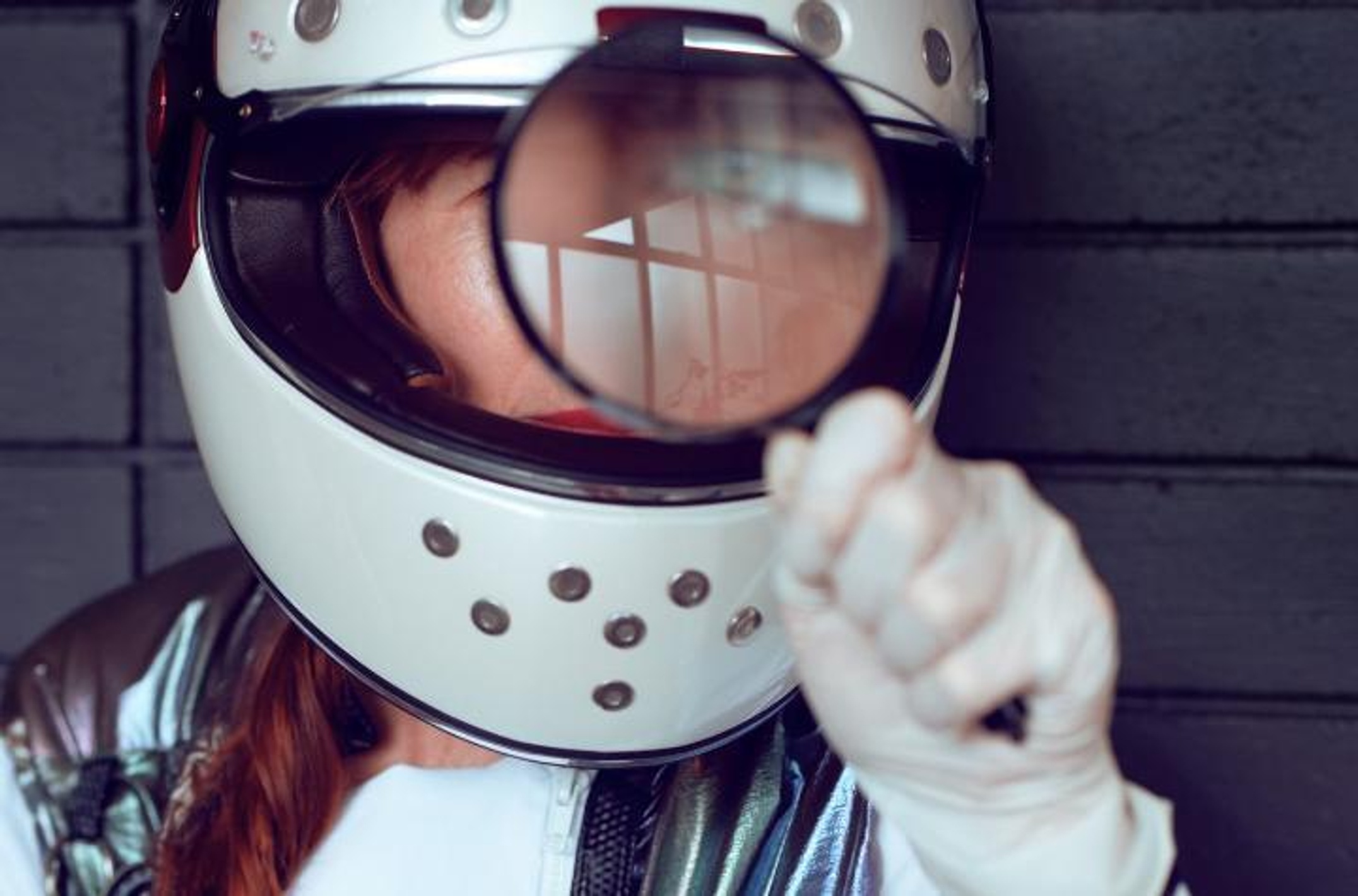 Lady in helmet looking through magnifying glass
