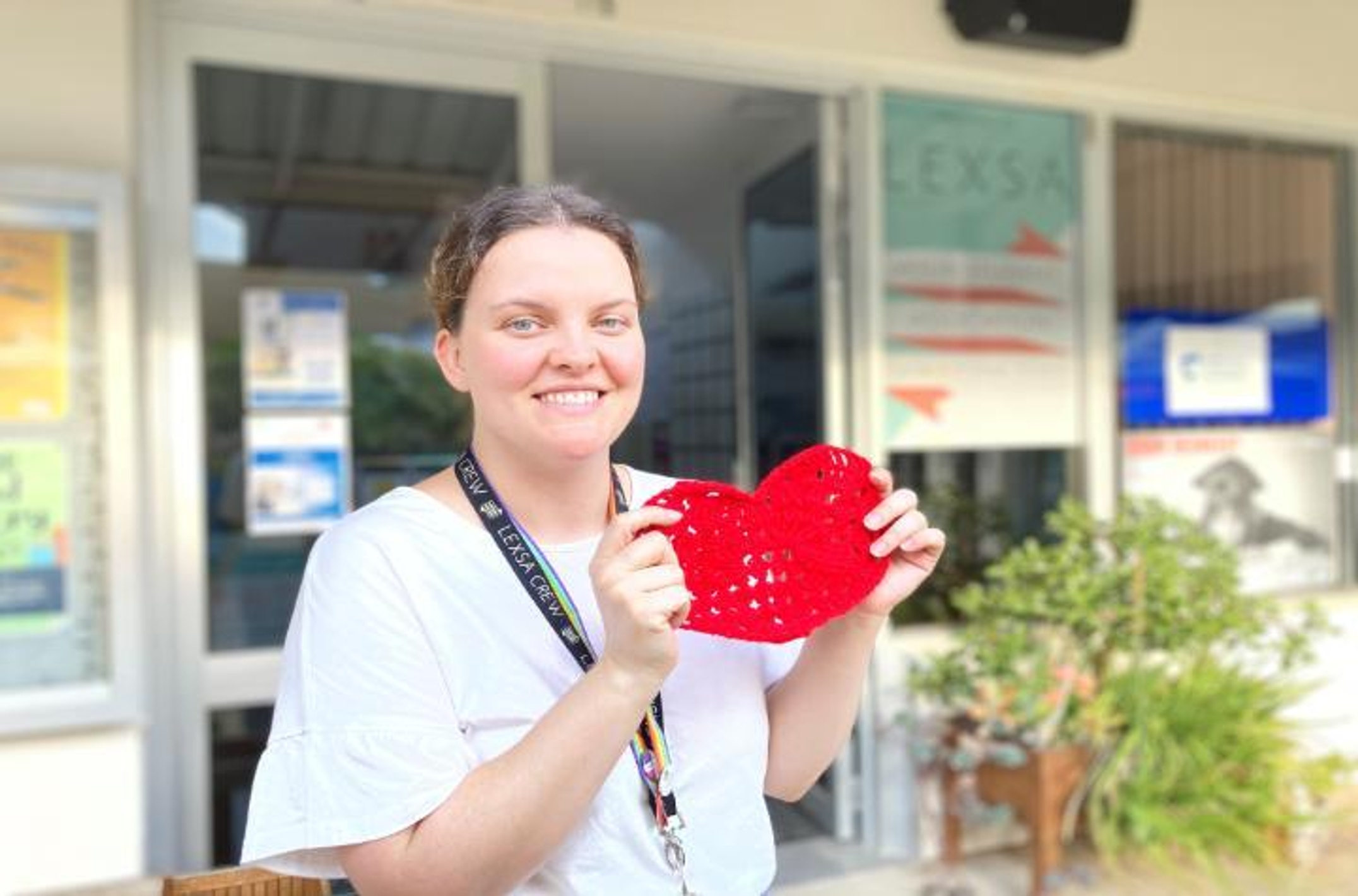 A woman holding a heart in front of the Lismore Lexsa office