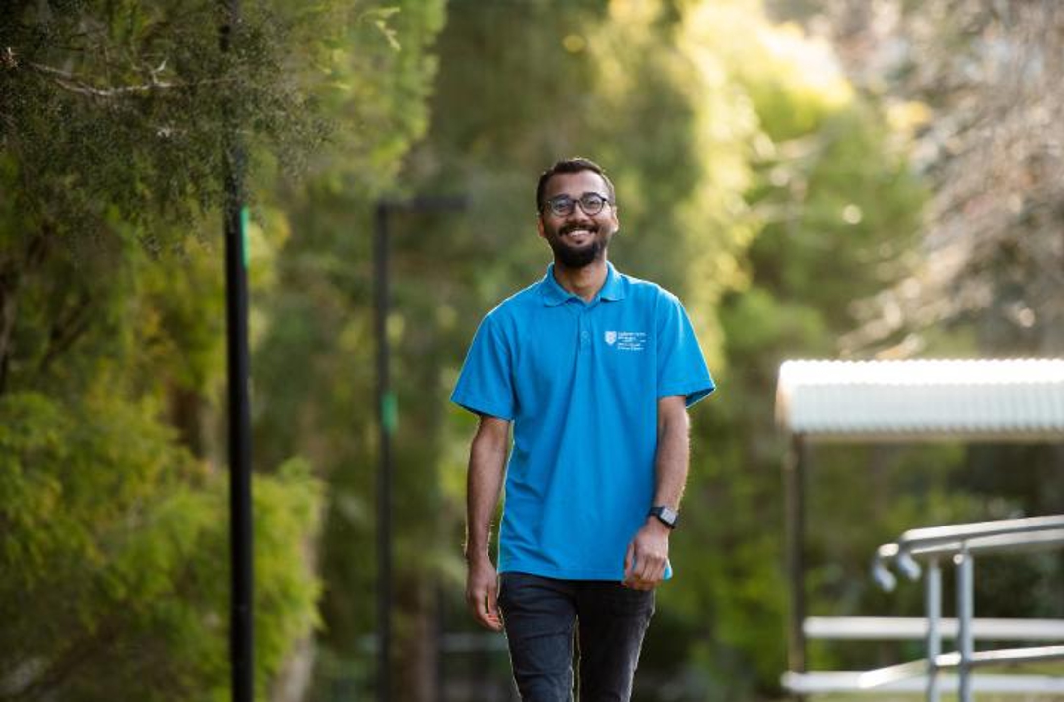 A student in a blue shirt walking on Lismore campus