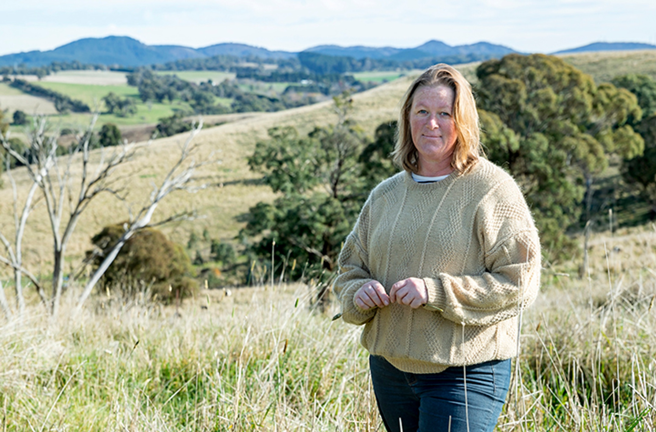 A woman stands in a panoramic landscape