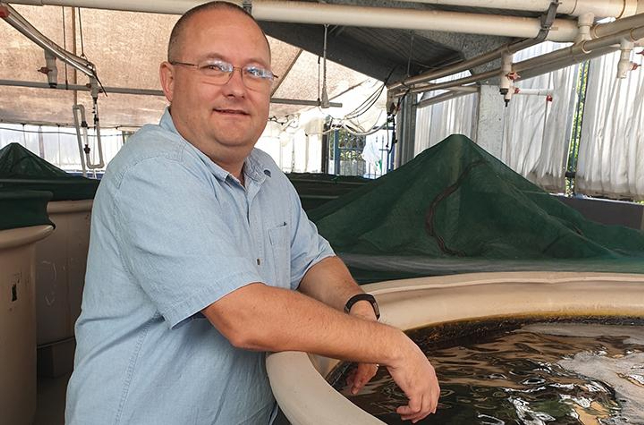 A man leaning against marine tanks.
