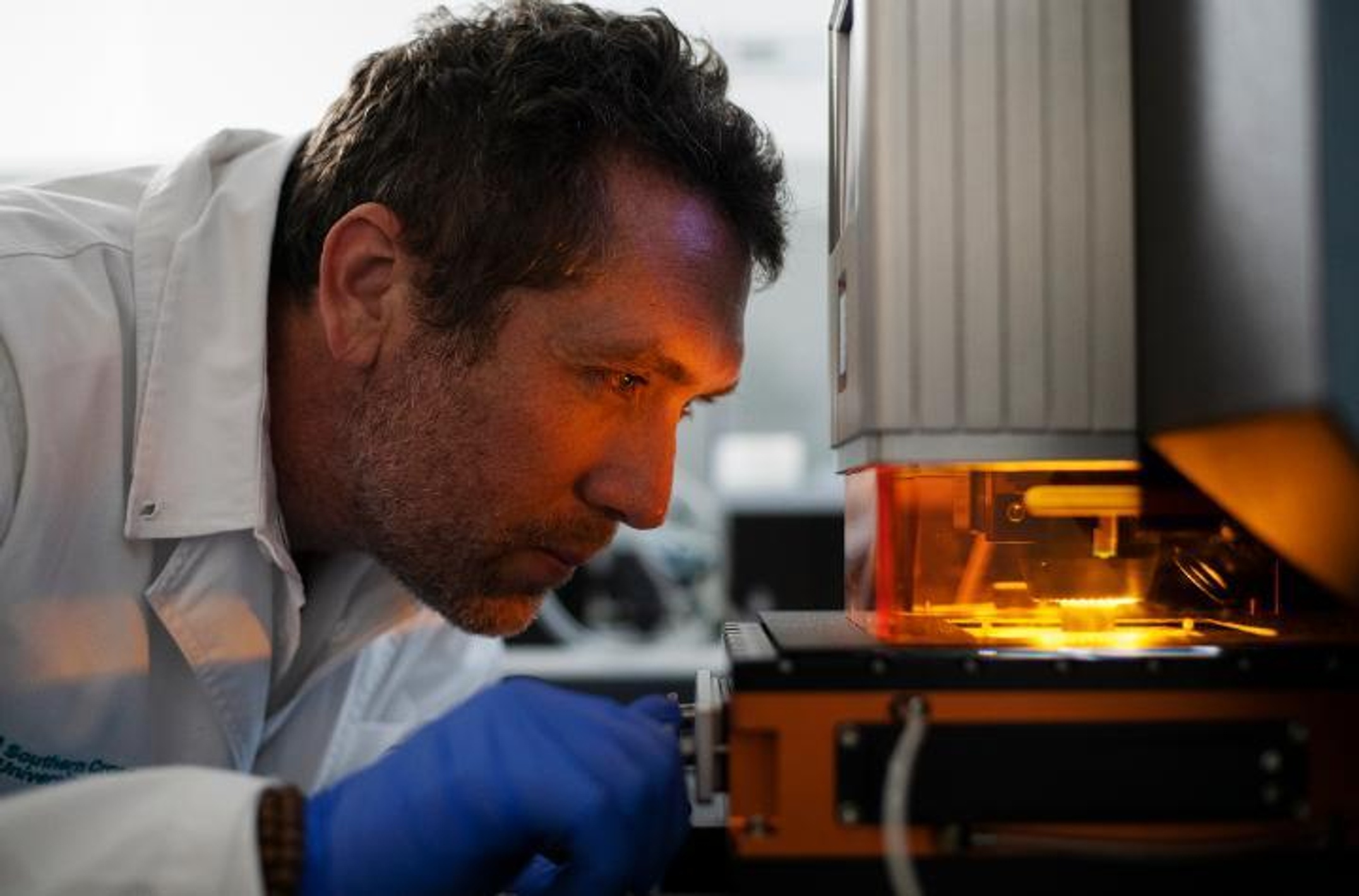 Scientist inspecting laser equipment doing fossil analysis