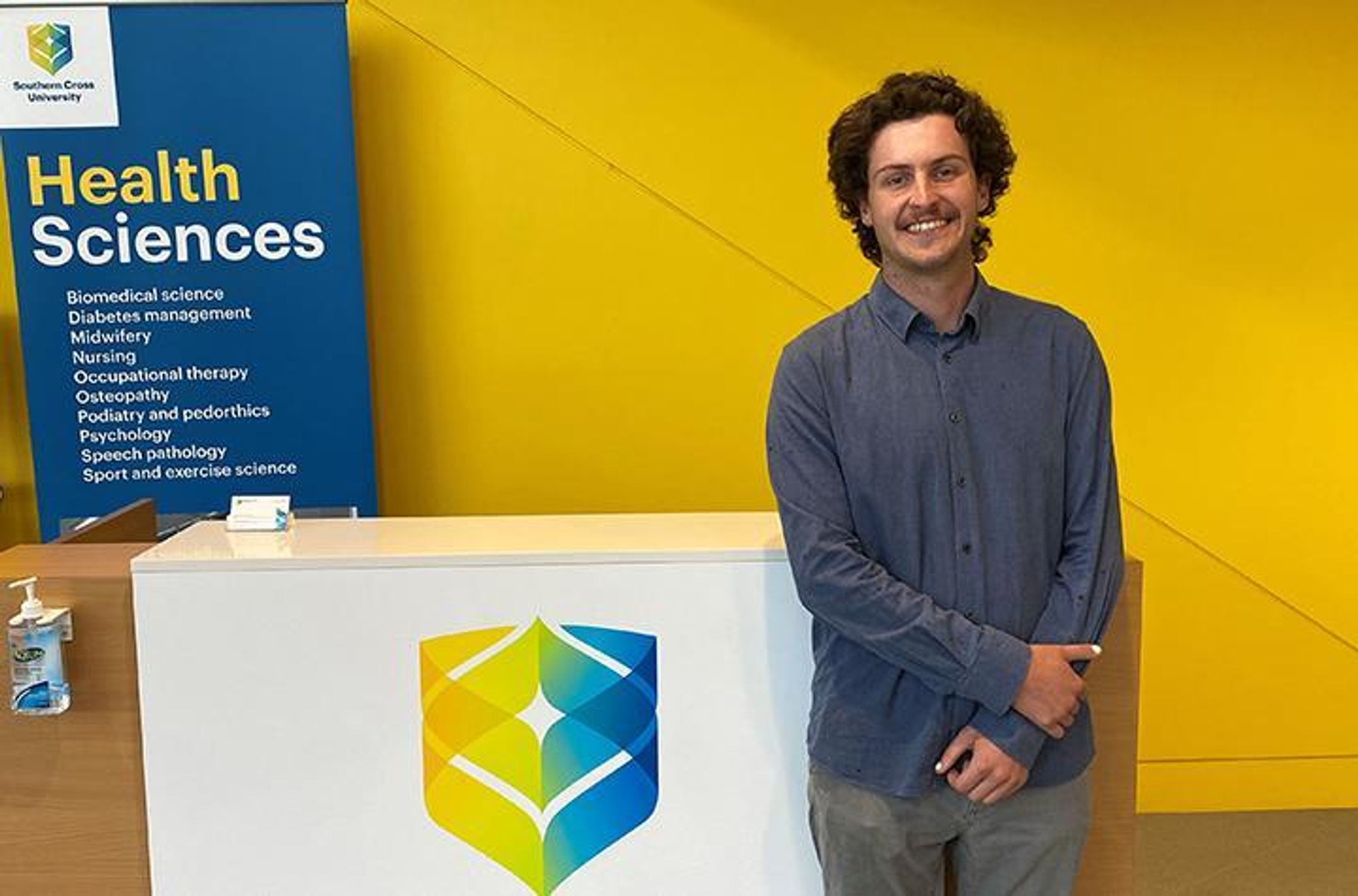 A man standing next to SCU health signage