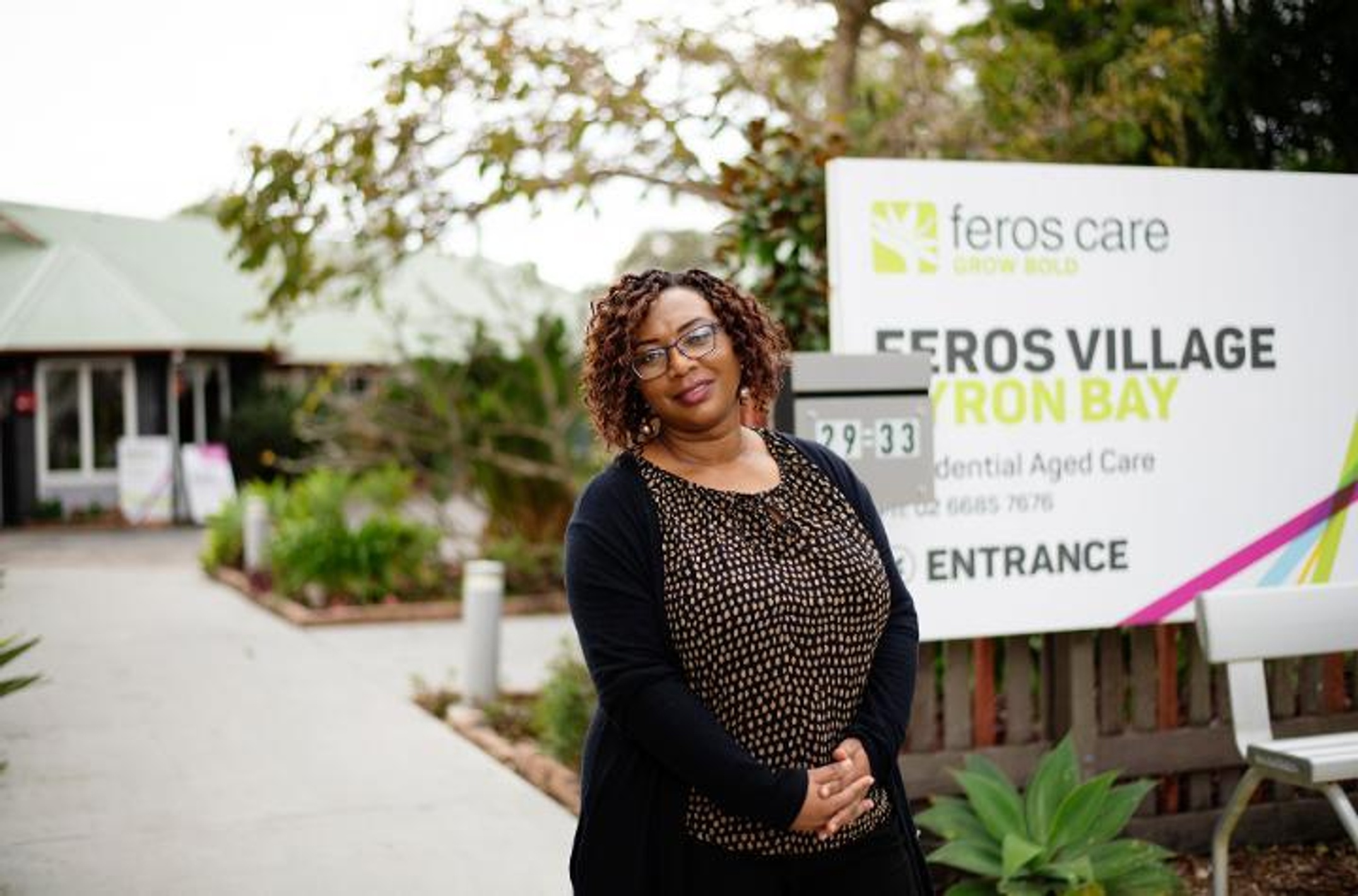Nurse standing in front of Feros Village sign