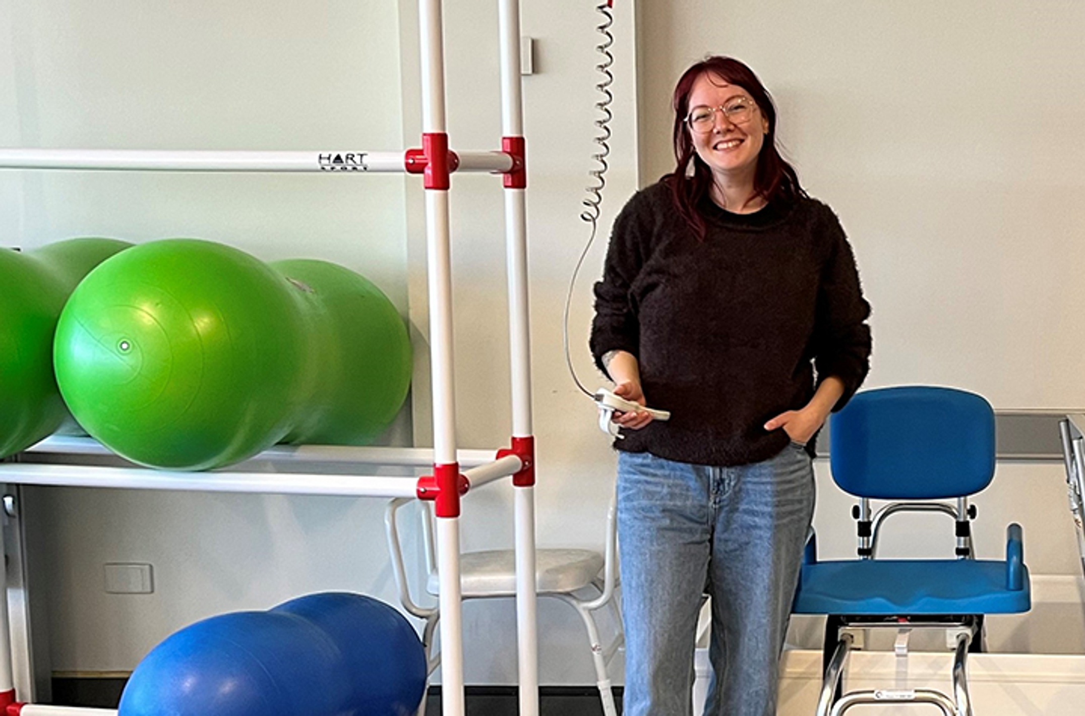 woman stands to one side of shelf with exercise balls