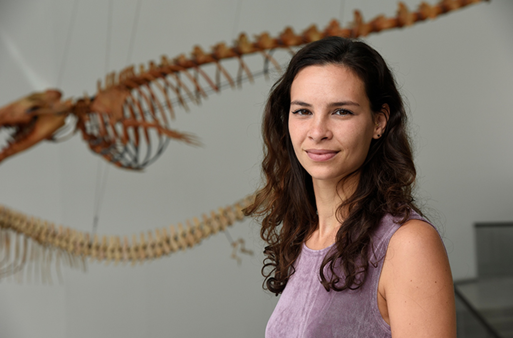 A woman posing for a photo with animal skeleton in background