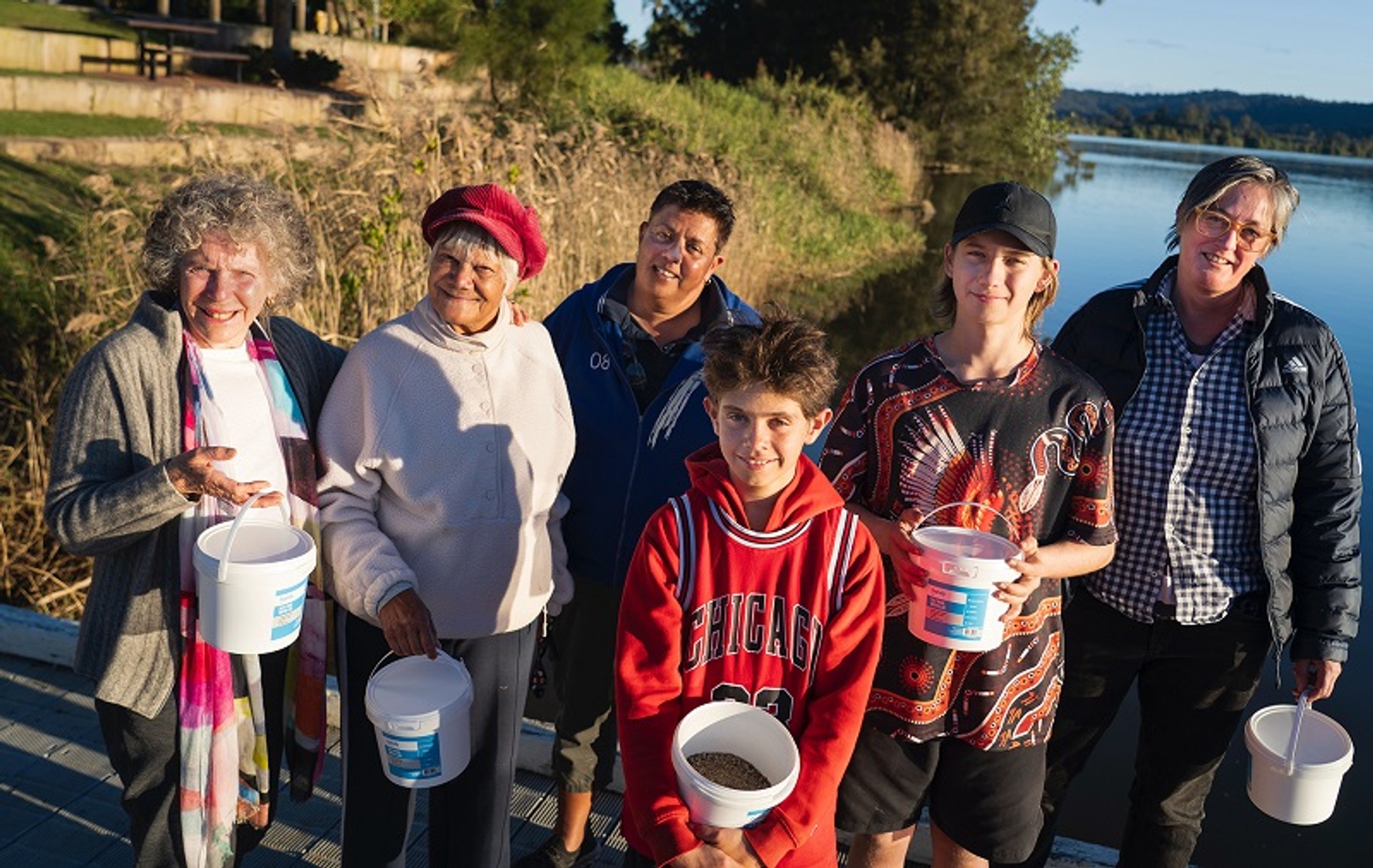 A group of citizen scientists with sampling buckets on the banks of a river