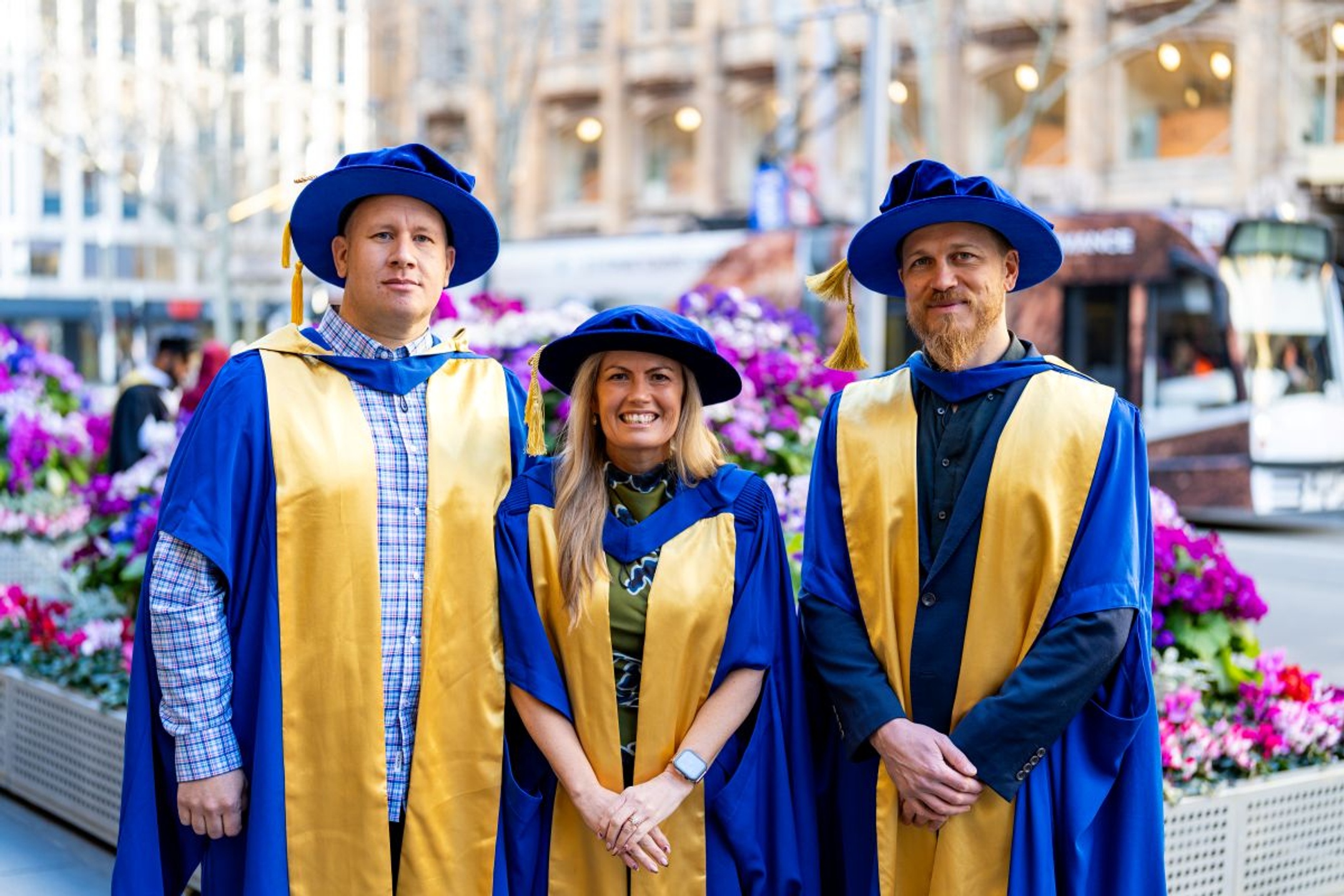 Two males and one female wearing graduation caps and gown