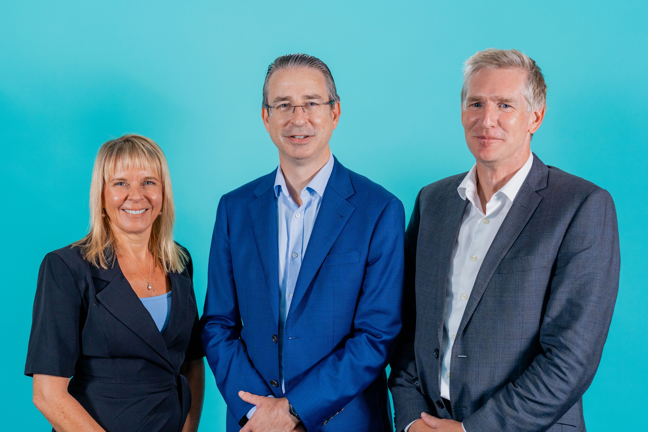 Three people posing in front of a blue background