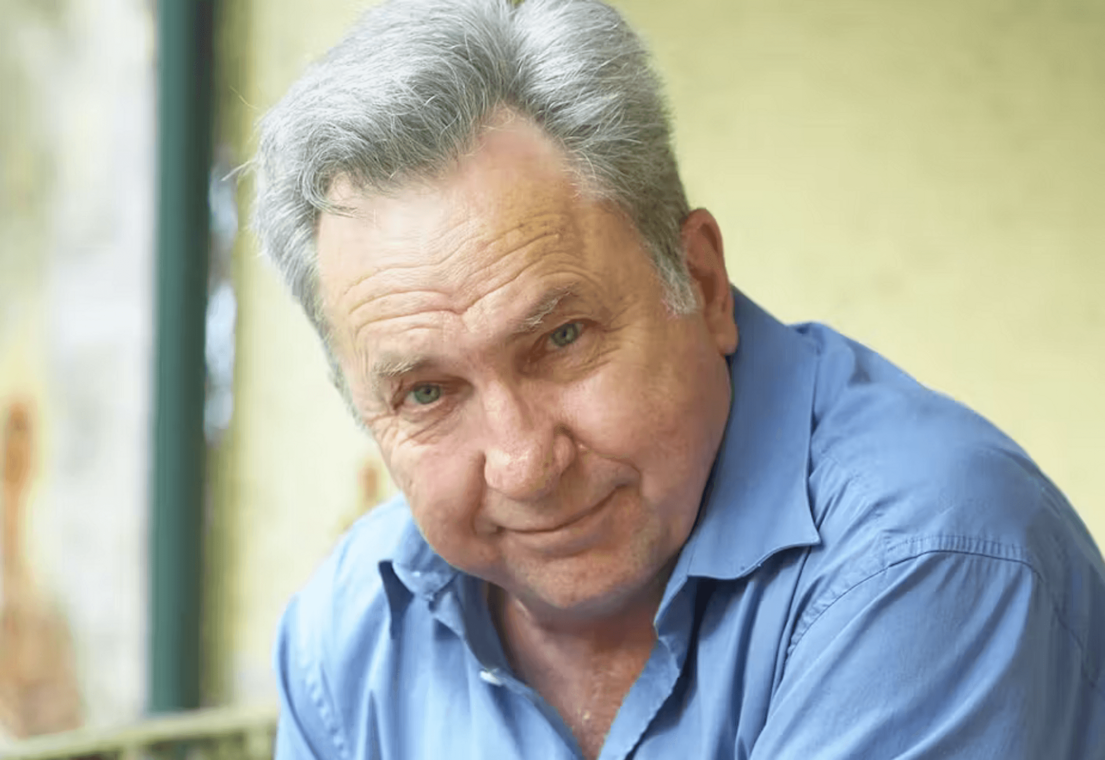 A man with grey hair wearing a blue shirt