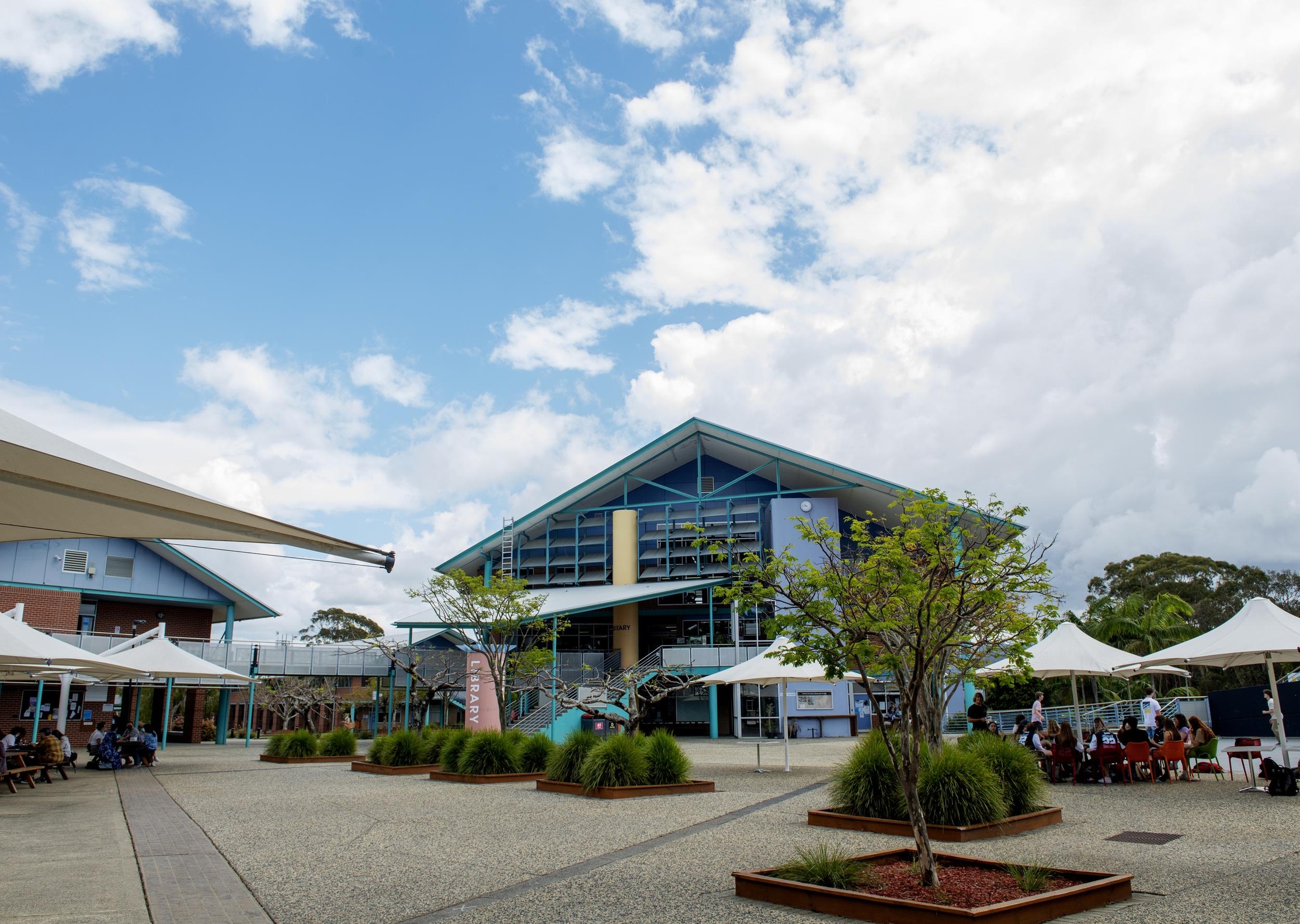 A wide angle view of the coffs harbour campus with green forested hills in the background