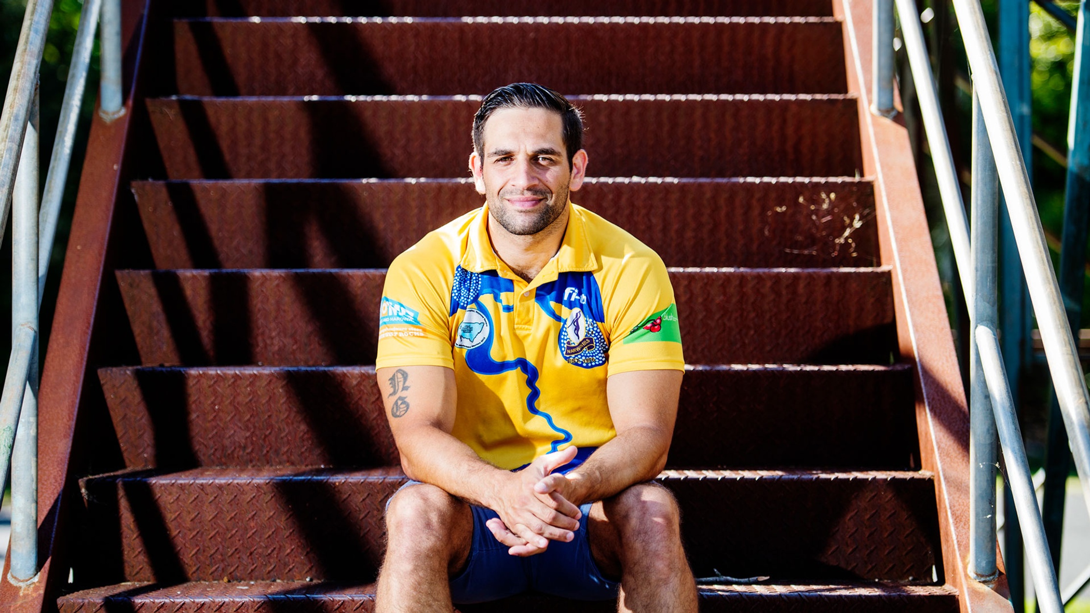 Indigenous man in sporting jersey sitting on stairs